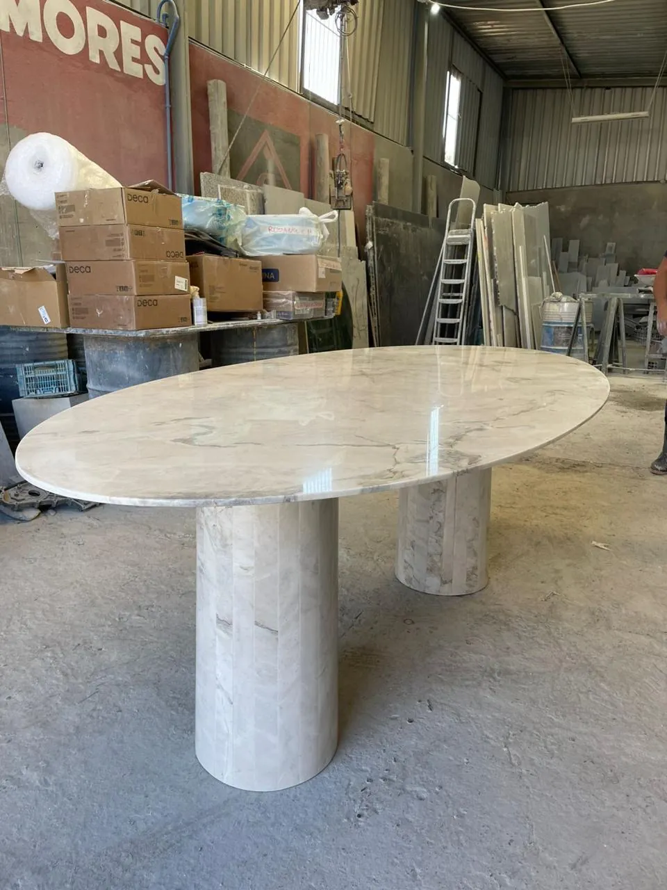 Mesa oval. Tampo e base cilíndrica em pedra clara.
